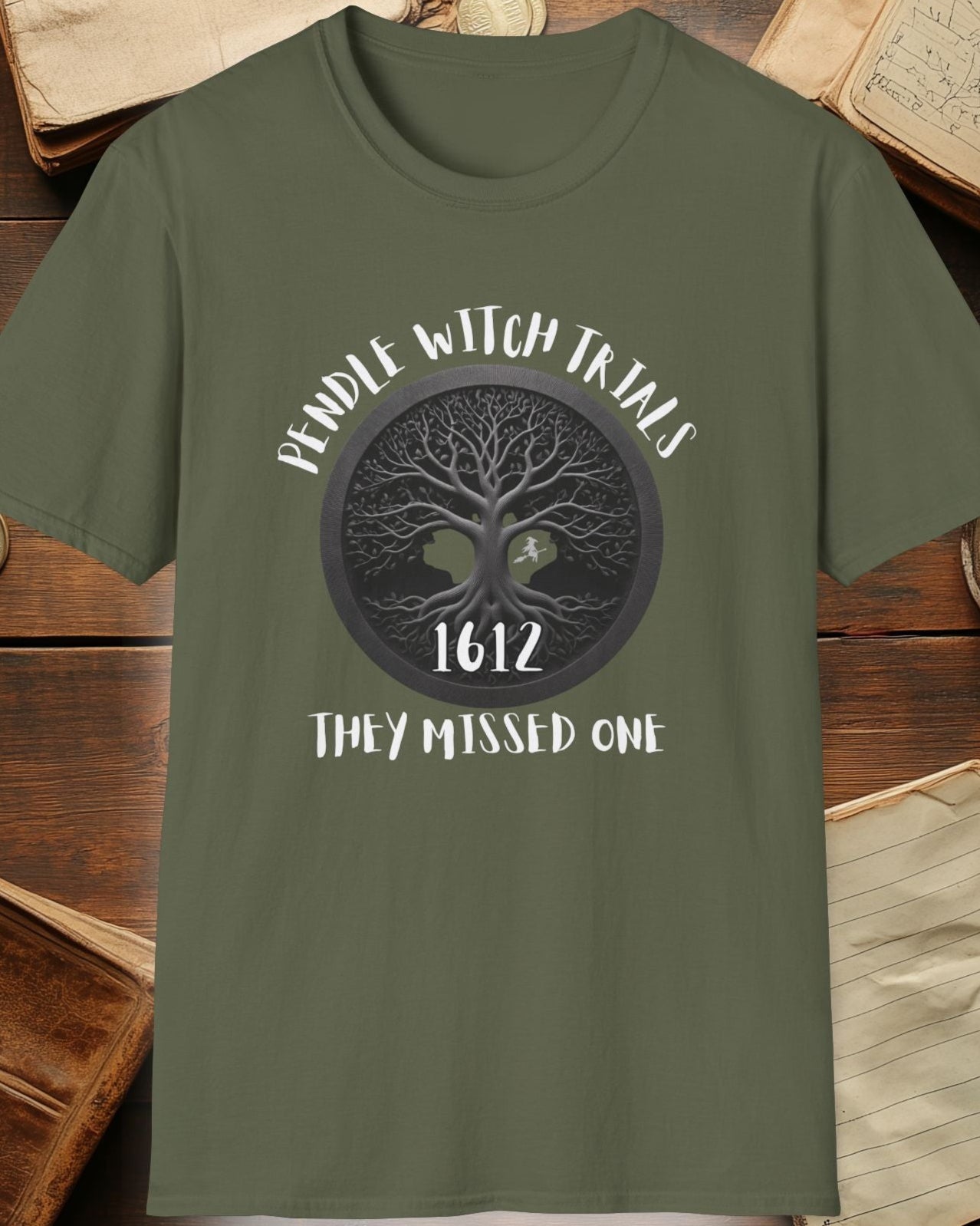 green tshirt with the text "Pendle witch trials, they missed one"