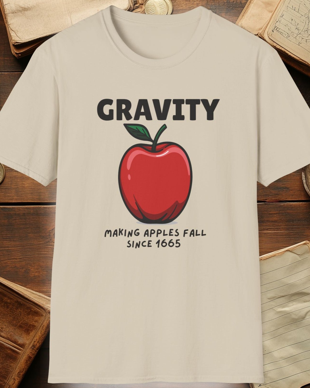 sand tshirt with a apple and the text "Gravity, Making apples fall since 1665"